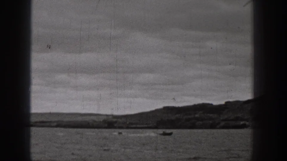 1938 Washington home-movie frame of a lake with distant small boats, low hills, and visible film wear.