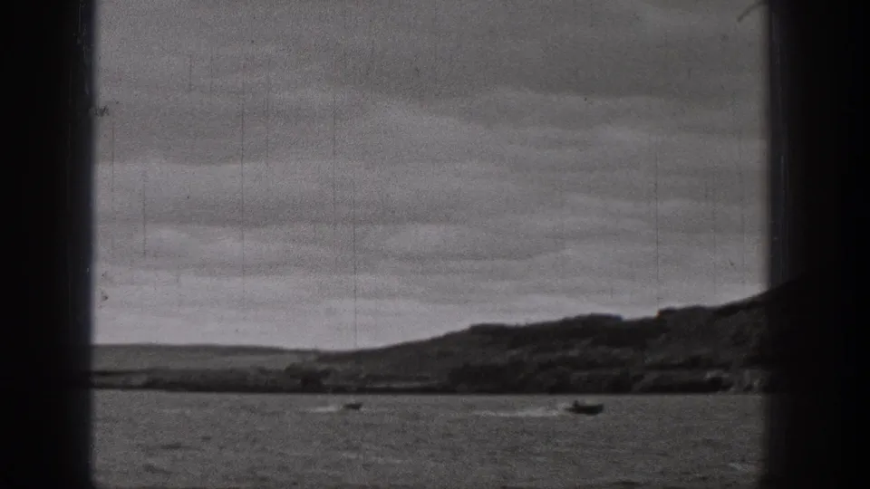 1938 Washington 8mm frame showing small boats on a lake or river with rolling hills and cloudy sky in the distance.