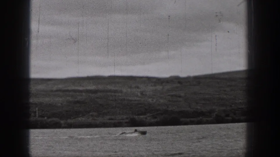 Black-and-white 8mm view from Washington in 1938, with a small boat on open water and a low hillside behind it.