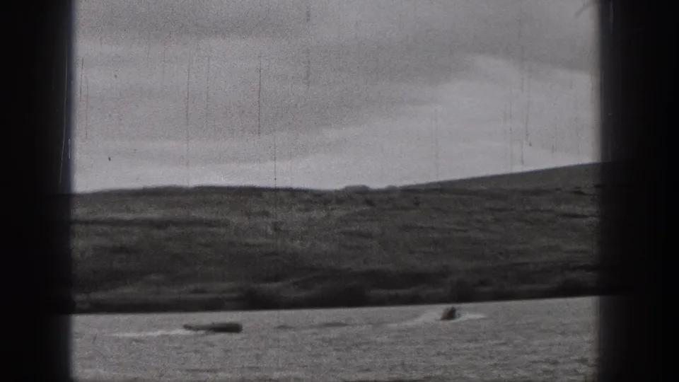 Late-1930s Washington 8mm frame showing cloudy sky, low hills, and small boats on a broad body of water.