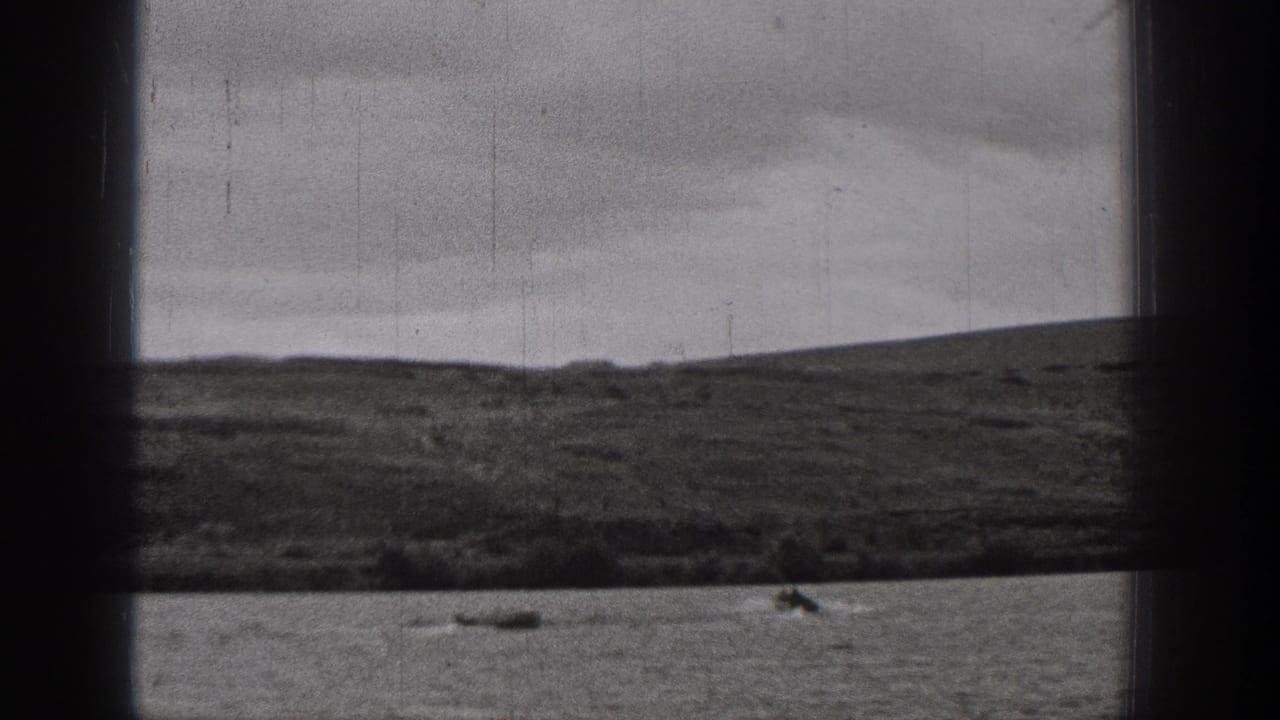 1938 Washington 8mm home-movie frame showing small boats on a lake with low hills and overcast sky in the background.