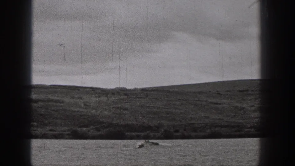 A distant small boat moves across a Washington lake in grainy 1938 black-and-white 8mm footage.