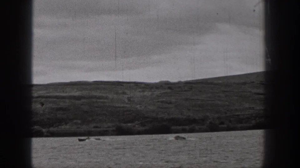 Distant lake boating appears in a 1938 Washington home-movie frame with hills, overcast sky, and visible film wear.
