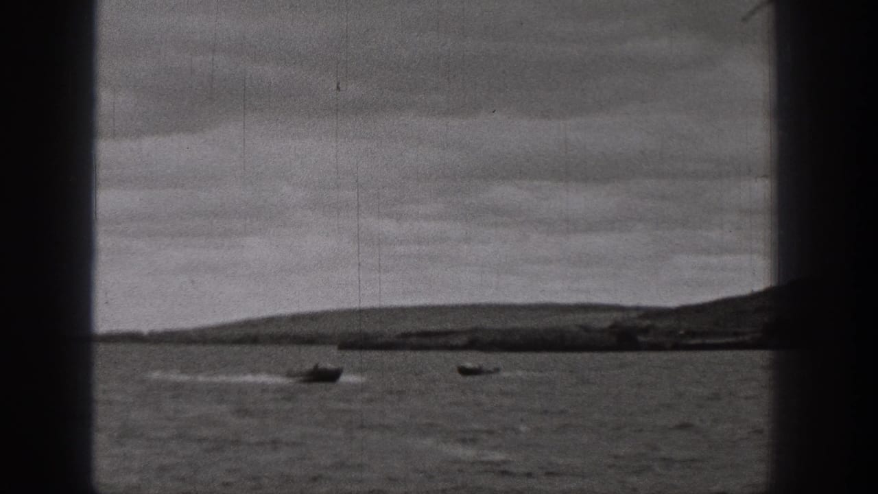 1938 Washington home-movie frame showing two boats on open lake water, with hills and an overcast sky in the distance.