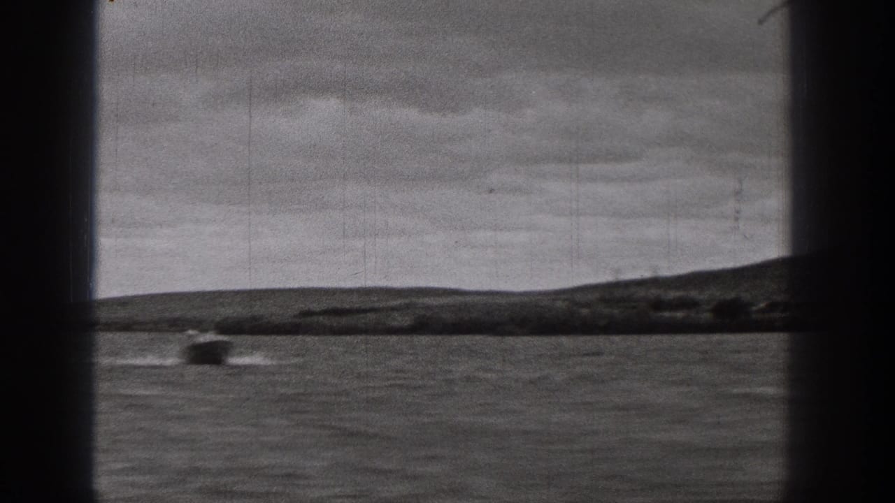1938 Washington 8mm frame showing a small boat moving across rippled water beyond a dark window frame and distant shore.