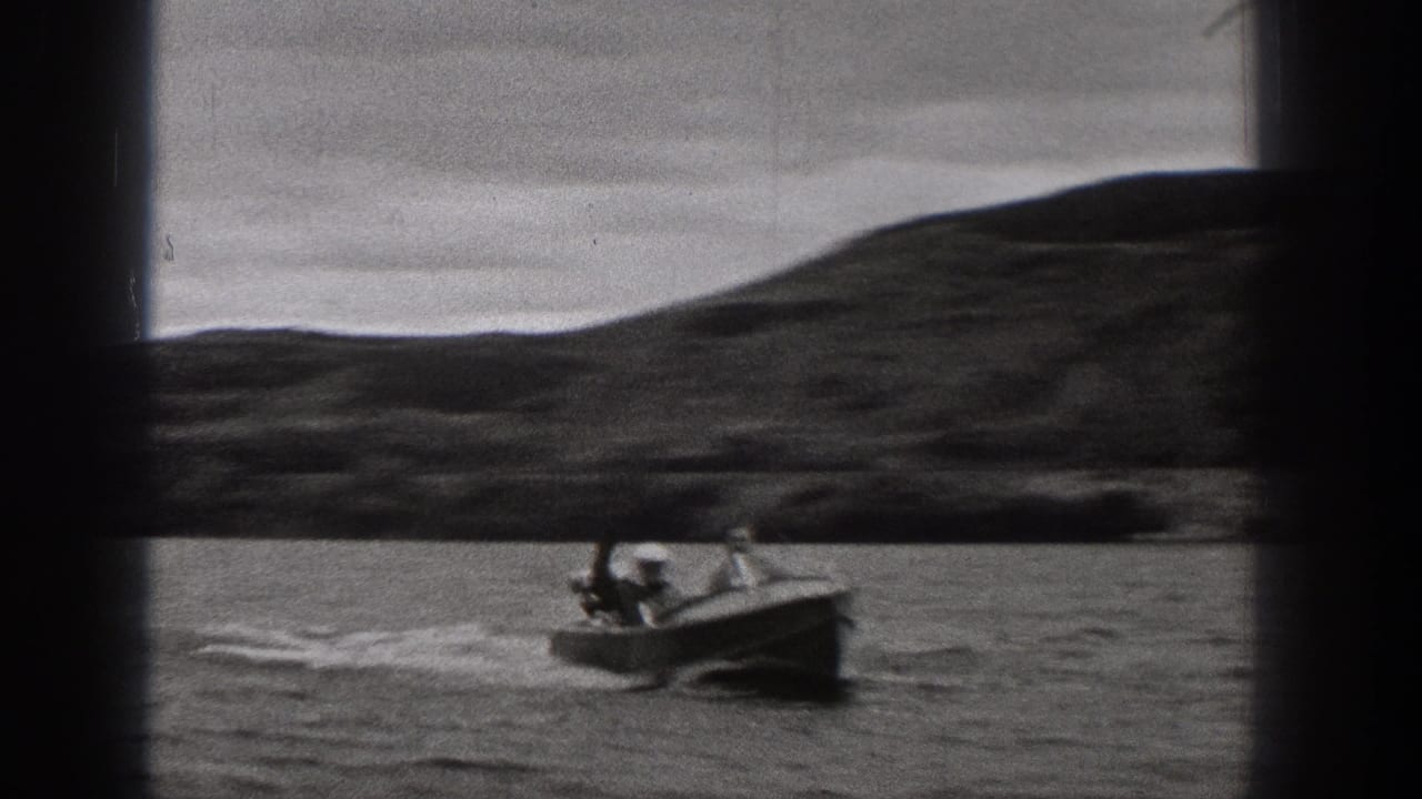 1938 Washington 8mm frame showing a small motorboat moving across a mountain lake under a cloudy sky.