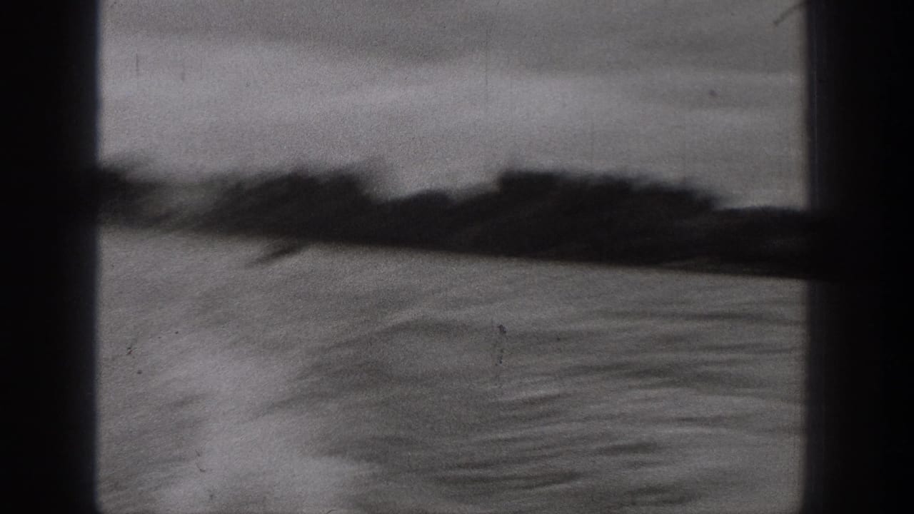 Motion-blurred 1938 Washington lake view with rippled water, dark shoreline, and cloudy sky on 8mm film.