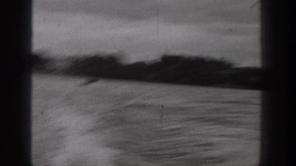 Motion-blurred 1938 Washington lake view with rippled water, dark shoreline, and cloudy sky on 8mm film.