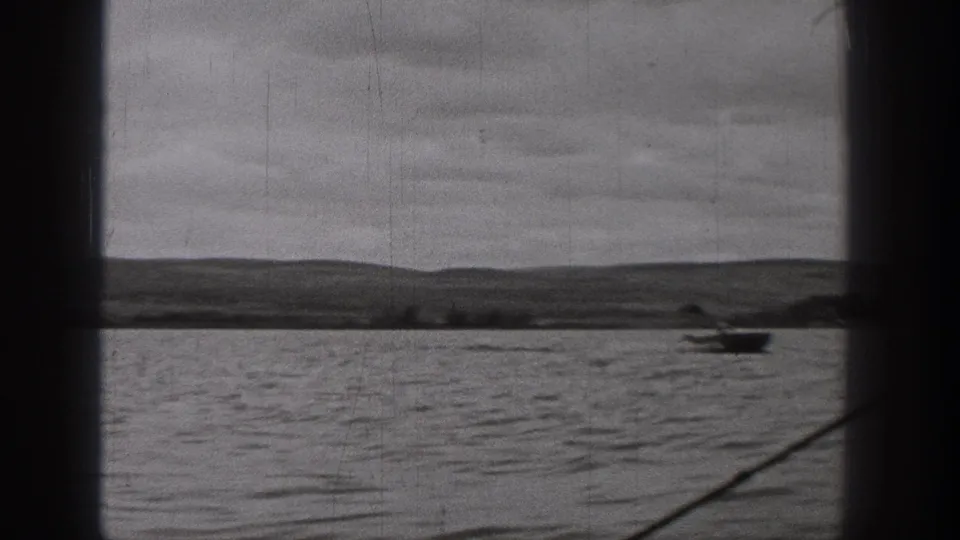 Wide 1938 Washington 8mm lake view with distant hills, cloudy sky, and a small boat near the right side.