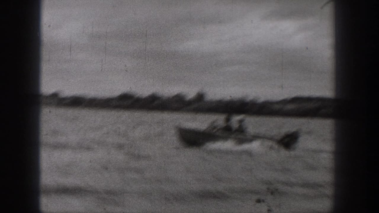 1938 Washington home-movie frame showing a motorboat moving quickly across the lake, with wake lines trailing behind it.