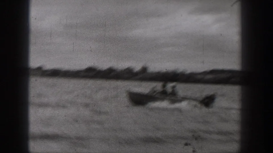 1938 Washington home-movie frame showing a motorboat moving quickly across the lake, with wake lines trailing behind it.