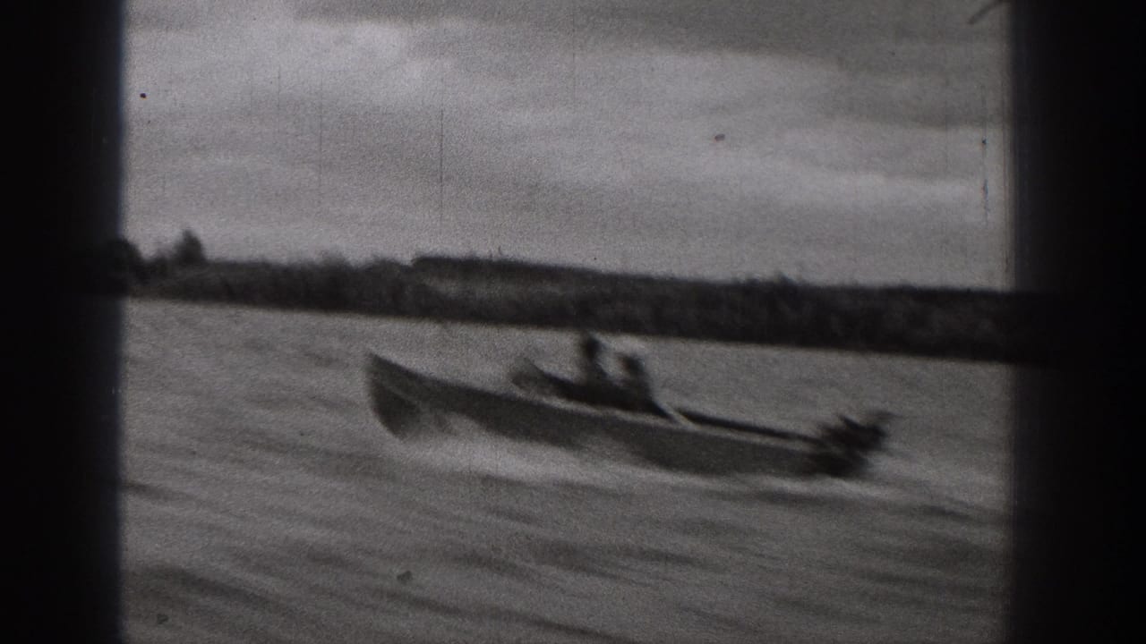 1938 Washington frame with a closer view of a motorboat and passengers moving across a lake under an overcast sky.