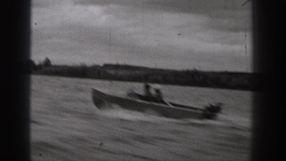 1938 Washington frame with a closer view of a motorboat and passengers moving across a lake under an overcast sky.