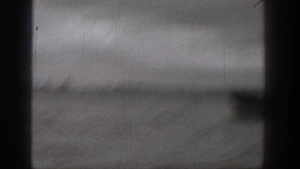 1938 Washington 8mm frame showing blurred water, a distant tree-lined shore, and dark film or boat edges during fast movement.