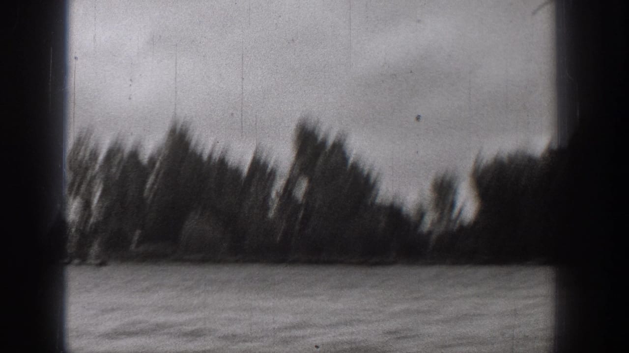 Black-and-white 8mm frame from a 1938 Washington boat ride, showing choppy water and a blurred line of lakeshore trees.