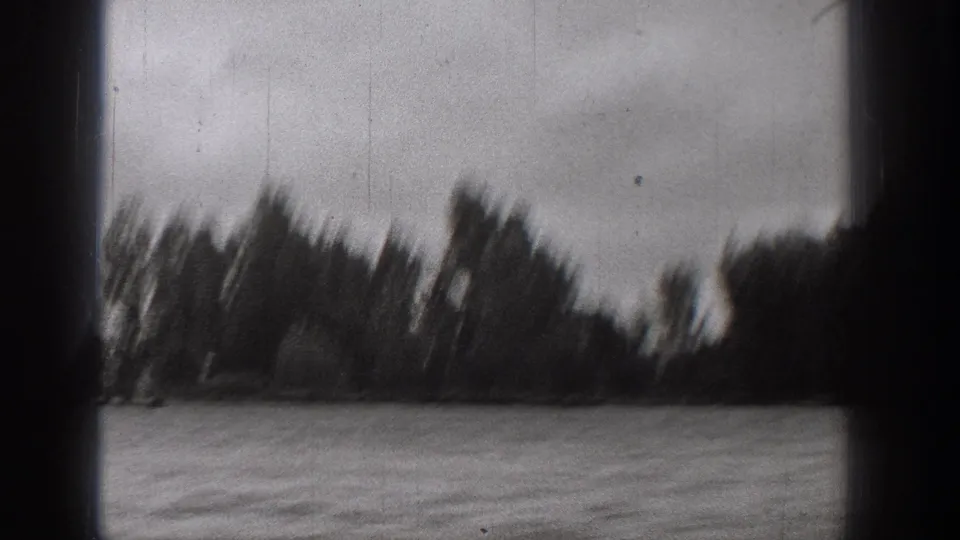 Black-and-white 8mm frame from a 1938 Washington boat ride, showing choppy water and a blurred line of lakeshore trees.