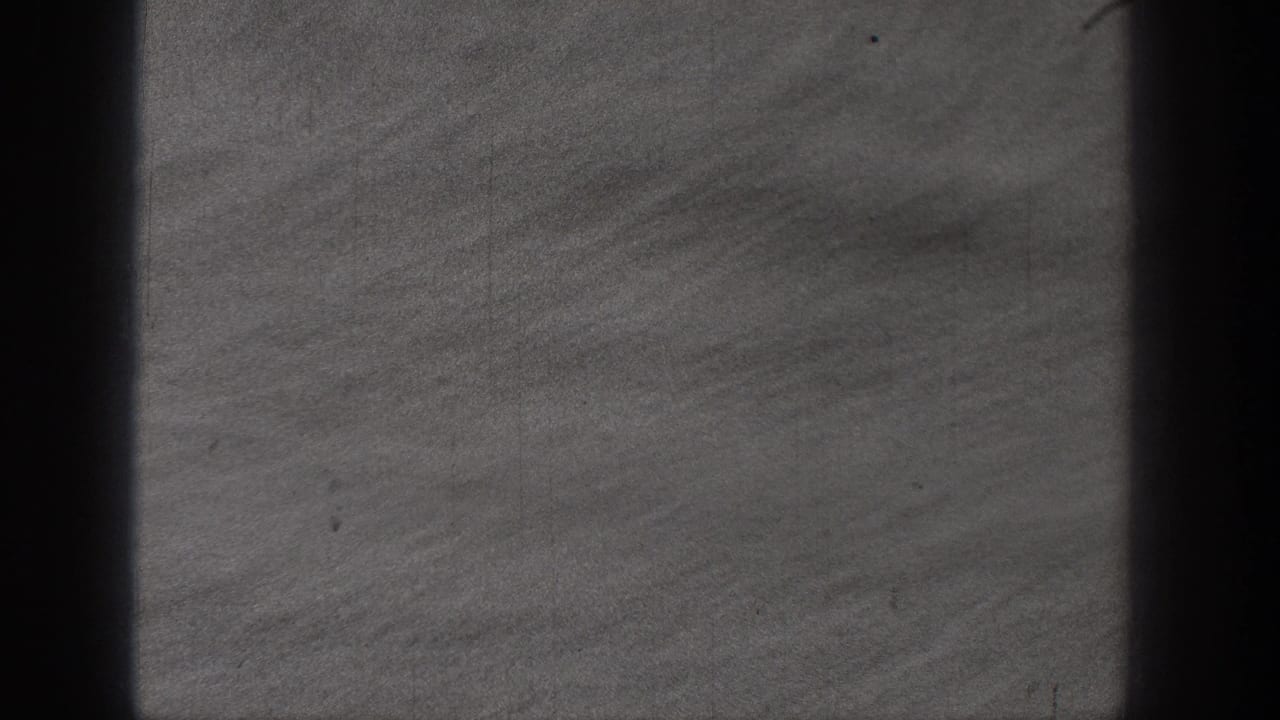 1938 Washington 8mm frame showing textured lake water, a soft distant shoreline, and dark edge shading from the moving boat view.