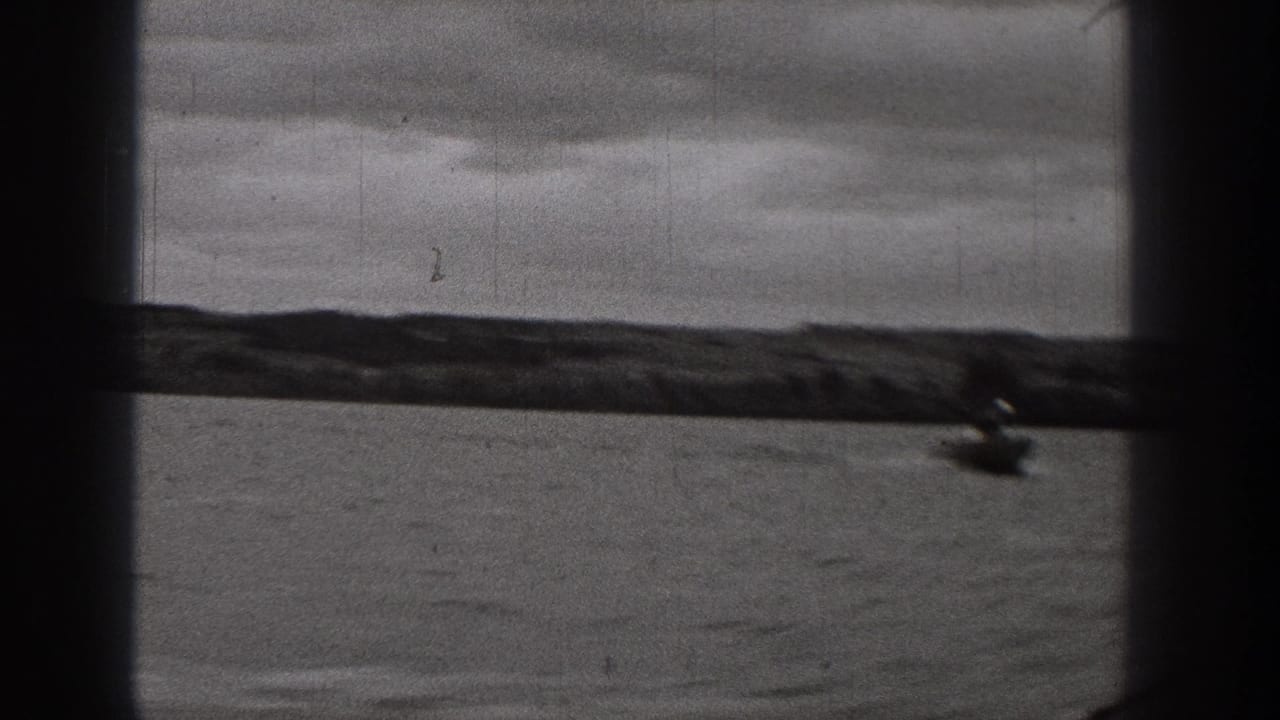 Distant boat near the right edge of calm water with low hills under clouds.
