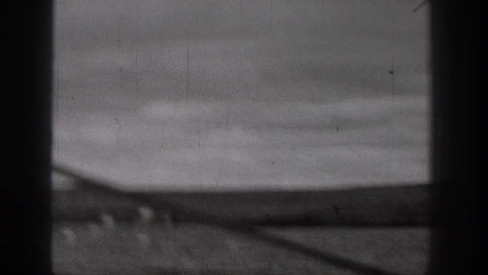 1938 Washington 8mm frame showing a blurred rural dirt road or plain through dark vertical bars, with hazy sky above.