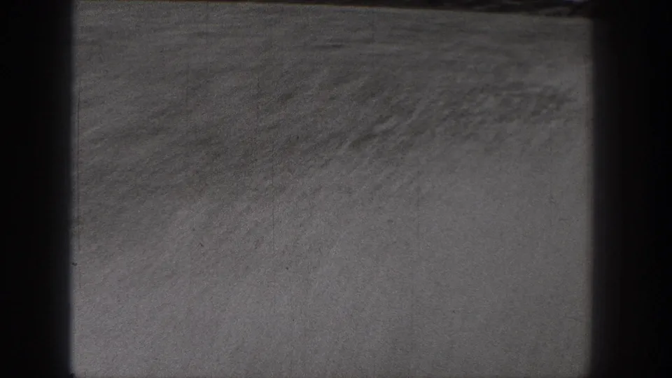 Monochrome 8mm view of dry open ground in Washington, with a faint horizon and dark framing at both sides.