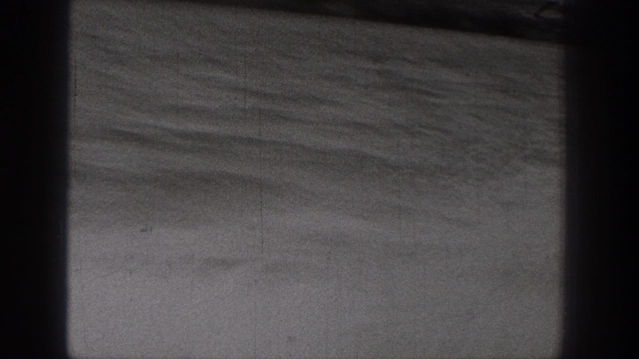 1938 Washington 8mm frame showing calm water, a low distant shore, and dark gate-like borders from the filmed viewpoint.