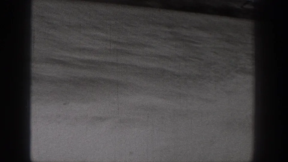 1938 Washington 8mm frame showing calm water, a low distant shore, and dark gate-like borders from the filmed viewpoint.