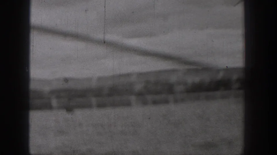 1938 Washington home-movie frame with blurred water, a darker shoreline strip, and visible film wear from a moving boat viewpoint.