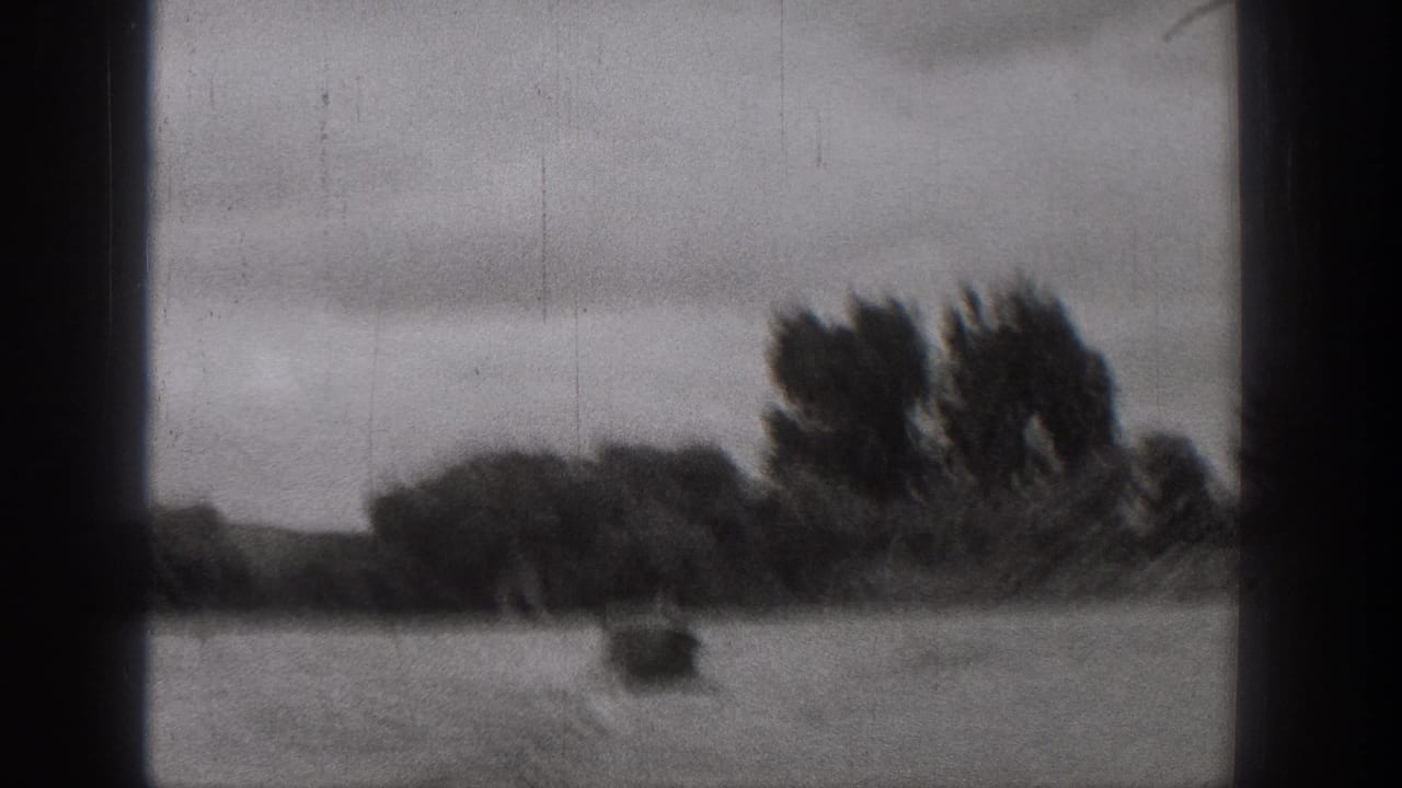 Black-and-white 8mm frame from Washington showing a small boat leaving a wake on a turbulent river under cloudy sky.