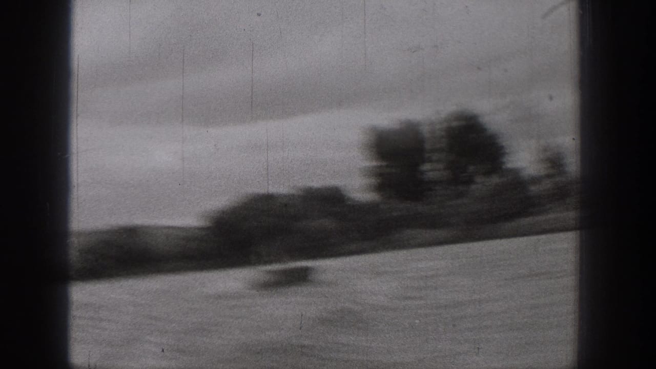 Washington 8mm home-movie frame showing a small blurred boat against a wide river and dark tree line under gray sky.