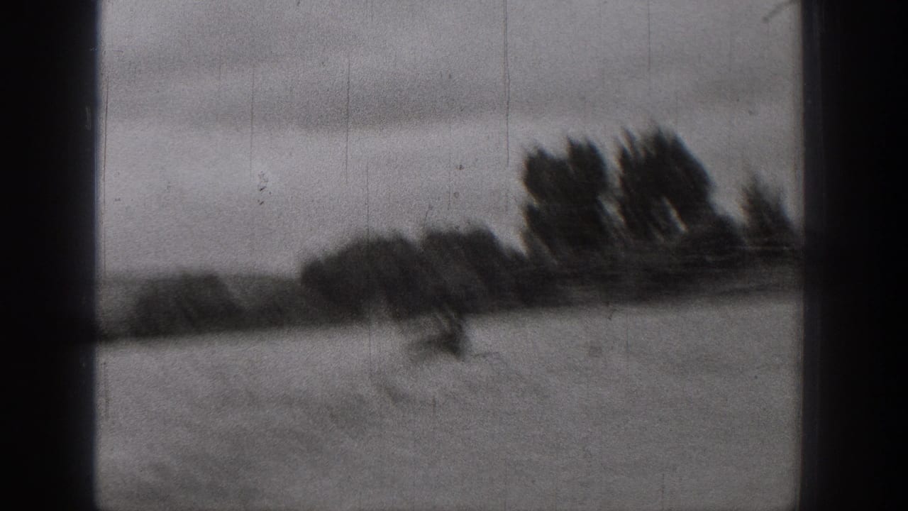 1938 Washington 8mm frame showing a dark-edged view over water toward trees and shoreline, with a boat blurred in motion near the left.