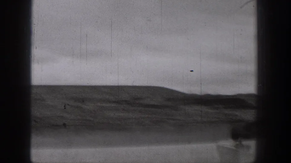 Black-and-white 8mm frame from the Washington clip showing open water, a low distant shore, and heavy dark borders from the film frame.