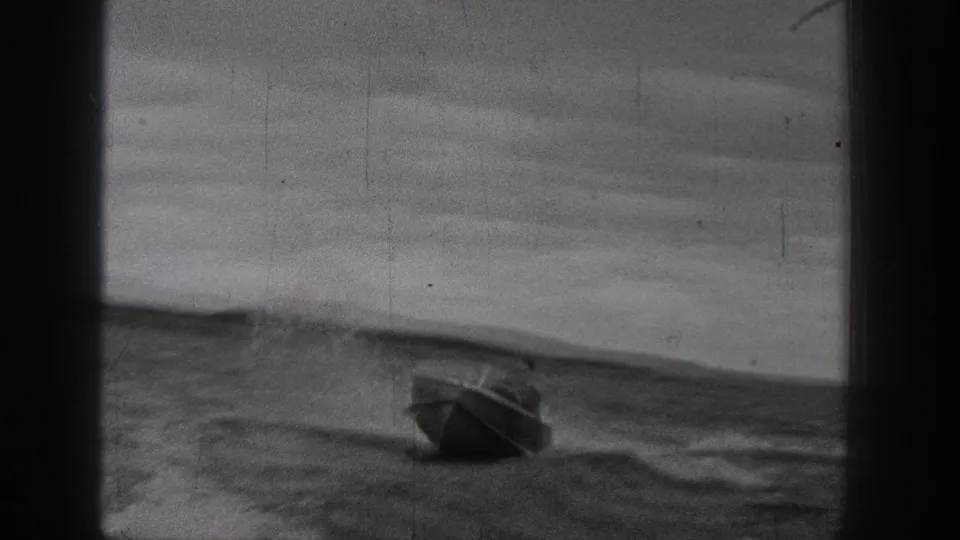 A small motorboat moves across choppy lake water in archival 1938 Washington home-movie footage, with hills faintly visible behind it.