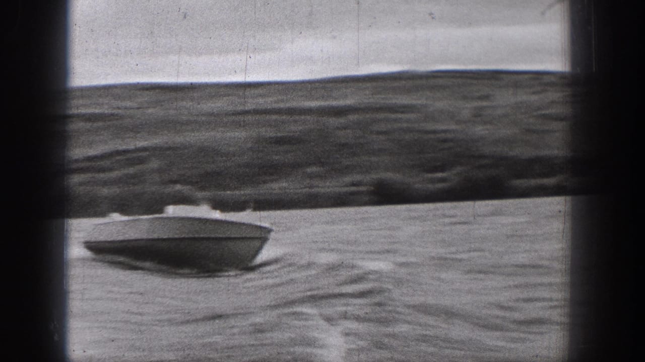 A closer view shows the small motorboat cutting across the lake in Washington, with rippled water, wake, and soft 8mm frame edges.