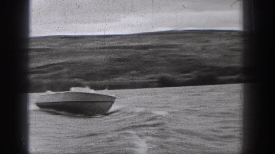 A closer view shows the small motorboat cutting across the lake in Washington, with rippled water, wake, and soft 8mm frame edges.