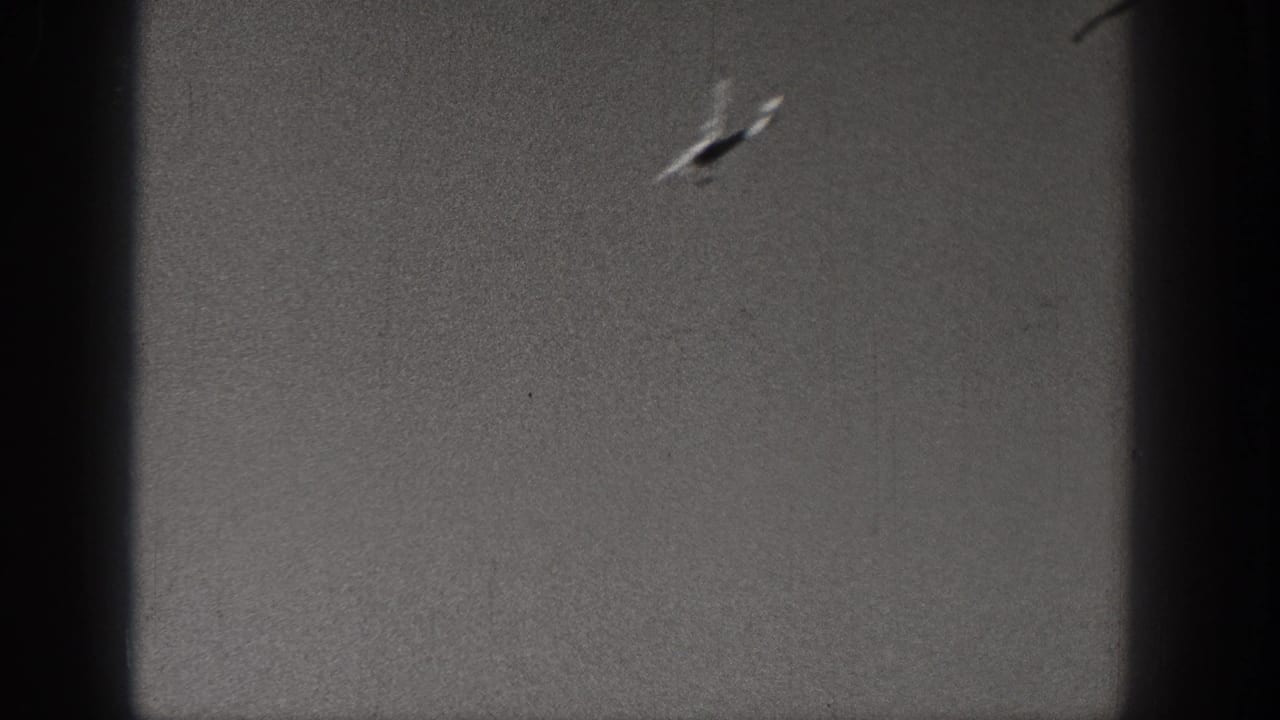 Distant airplane near the upper right of a scratched sky frame.