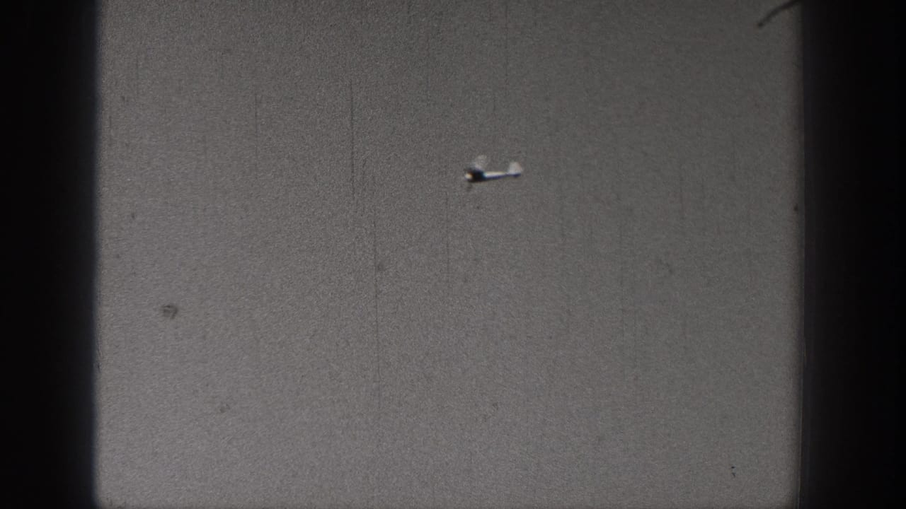 Distant small airplane sits lower in the frame during the 1938 Washington home-movie aerial maneuver.
