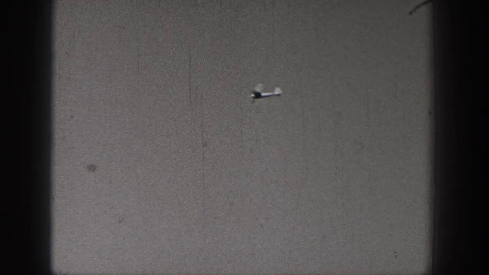 Distant small airplane sits lower in the frame during the 1938 Washington home-movie aerial maneuver.