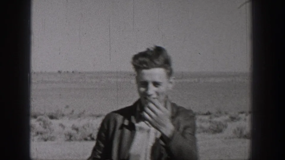 A young person appears in the final Washington 8mm frame, standing before open ground and distant low horizon.