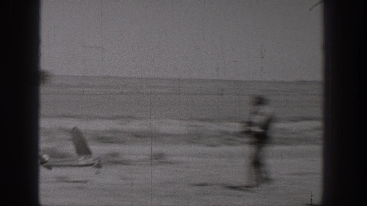 1938 Washington home-movie frame showing a small model airplane and a blurred standing figure in an open outdoor area.