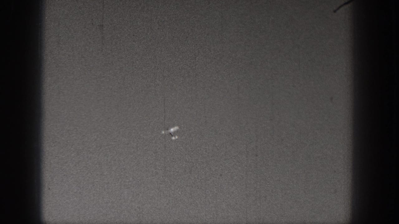 1938 Washington 8mm frame showing a small pale aircraft-like shape low in the grainy gray field.