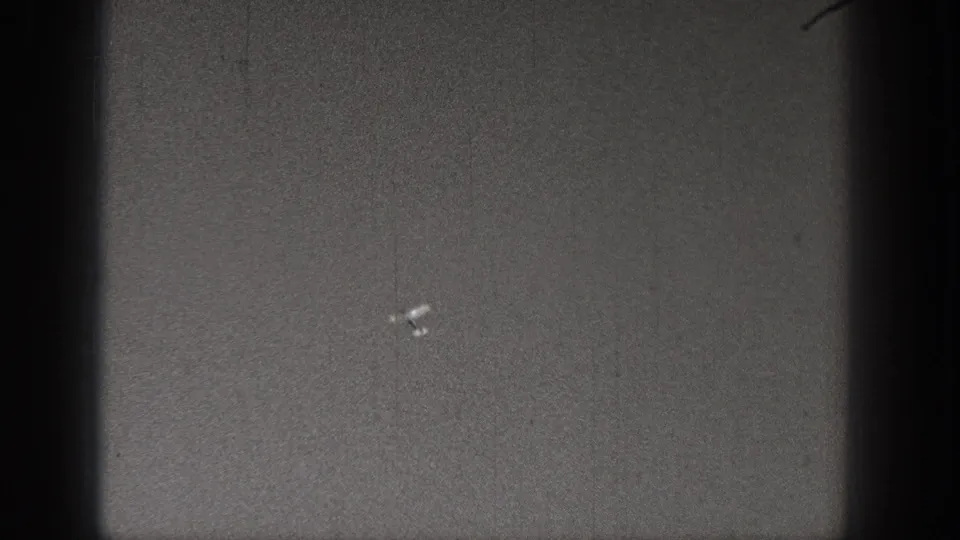 1938 Washington 8mm frame showing a small pale aircraft-like shape low in the grainy gray field.