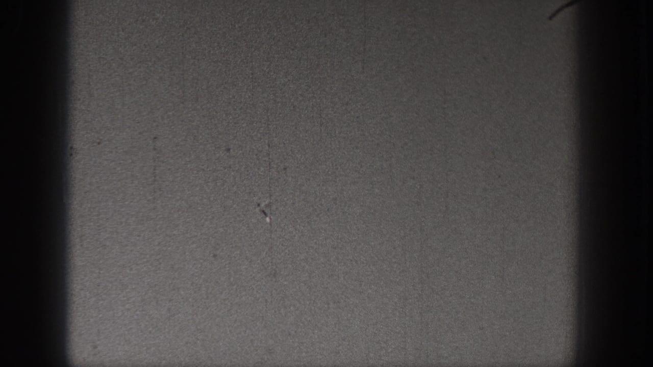 1938 Washington 8mm frame showing a dark, grainy sky area with film gate shadowing and small surface marks.