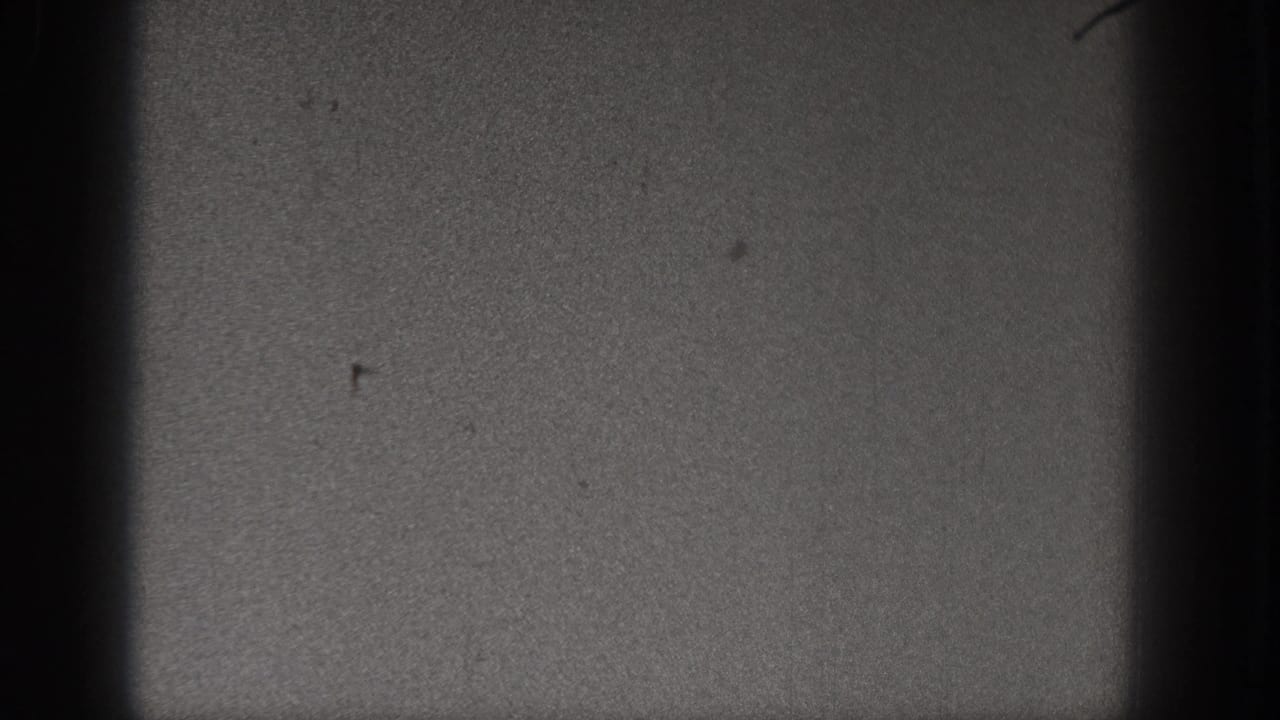 1938 Washington 8mm frame showing dark sky texture, small surface marks, and pronounced gate shadow along the frame edge.