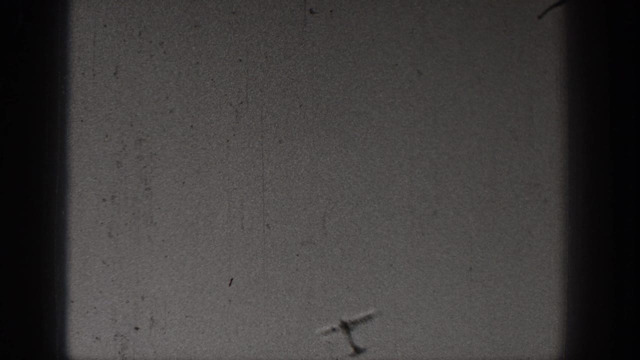 Mostly blank sky and film gate edges with scratches and dust visible.
