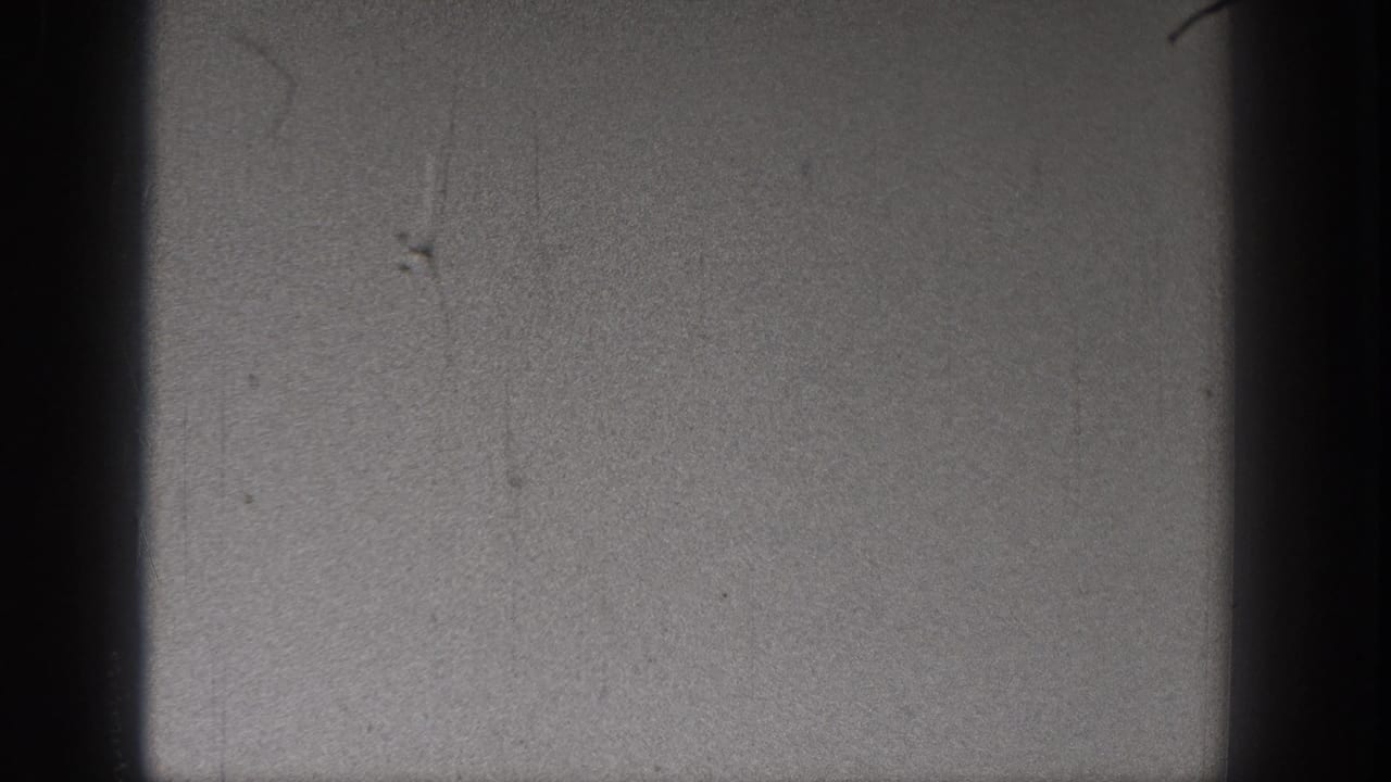Sky and film gate edges with scratches and no distinct people visible.