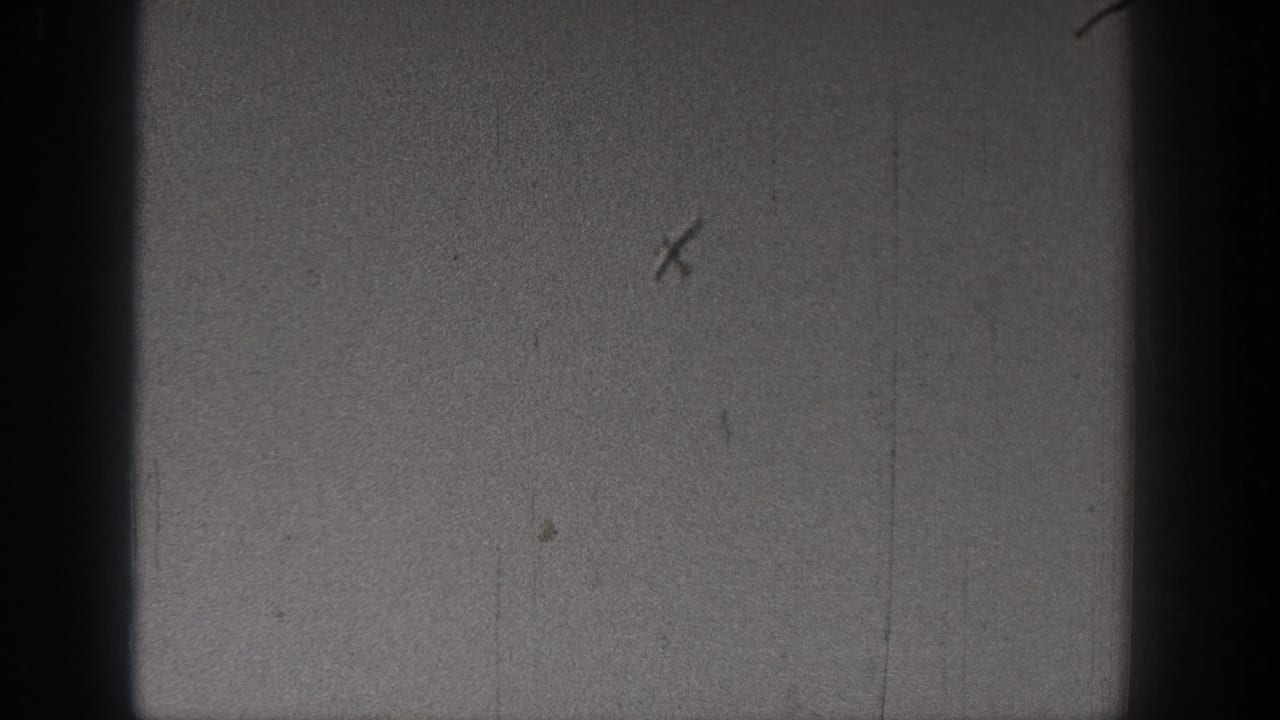 Black-and-white 8mm frame from the Washington 1938 clip with mostly sky, dark gate edges, and visible scratches, with no clear figures present.
