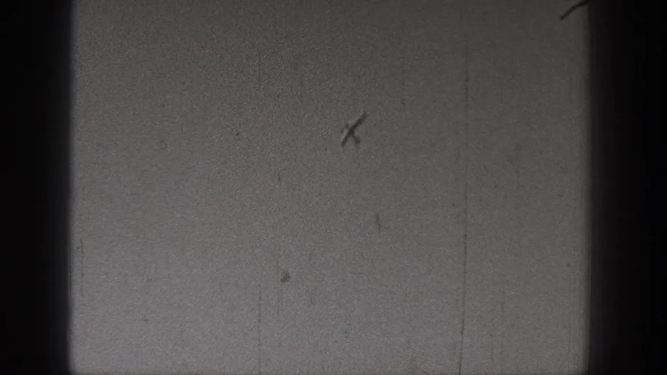 Black-and-white 8mm frame from the Washington 1938 clip with mostly sky, dark gate edges, and visible scratches, with no clear figures present.