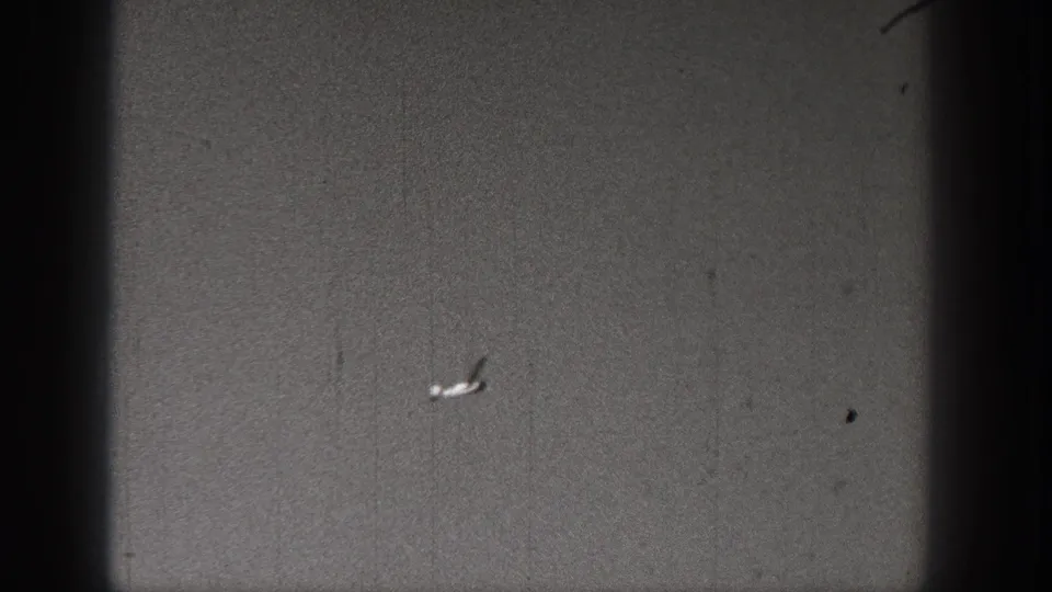 A small plane or model aircraft appears in the sky over an open Washington landscape in 1938 home-movie footage.