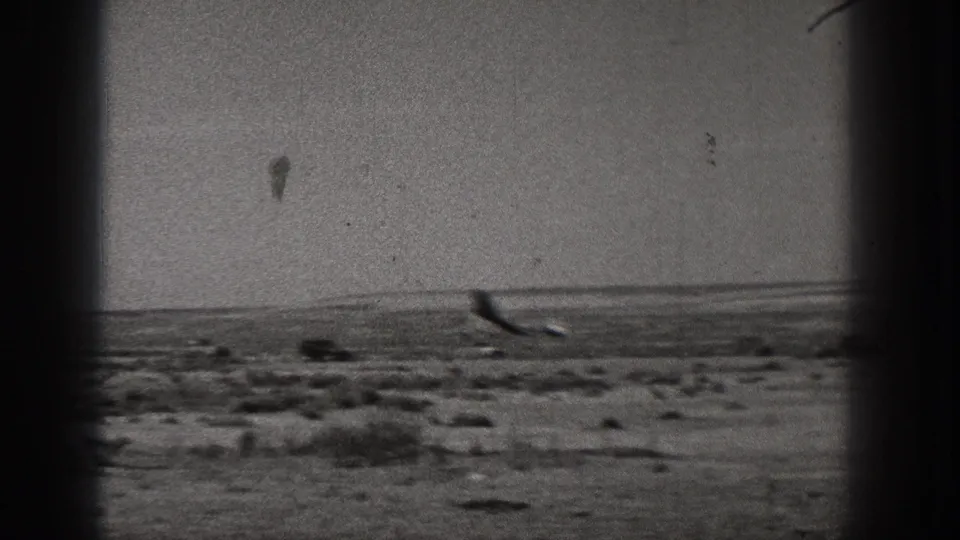 The small plane or model aircraft appears low over scrubby terrain in the 1938 Washington home-movie scene.
