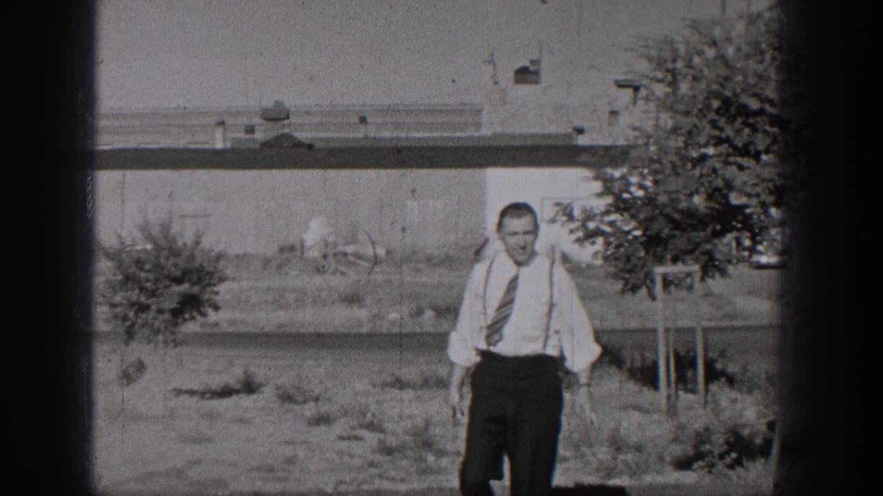 A man in shirt, tie, and suspenders walks toward the camera in a 1938 Washington home-movie street-side scene.